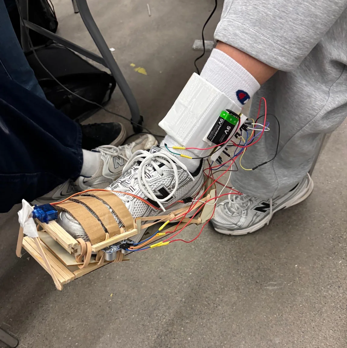 AutoCleat being worn, with wiring to the ankle-mounted controller